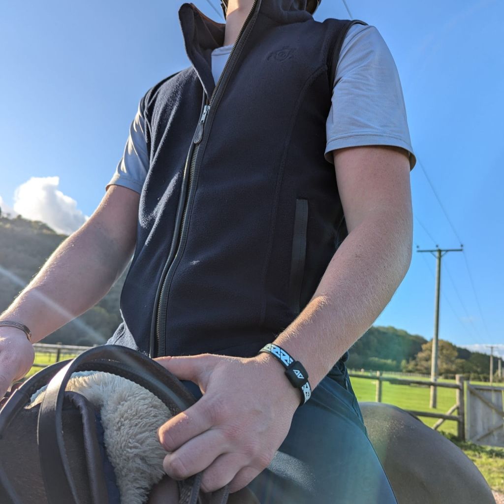 Archie Cloke sitting on a horse with a scenic background wearing his AV Edge Legend Wristband with with EF technology, frequencies, not magnets, that may protect against modern technology EMFs and improve health and performance by stimulating the production of adenosine triphosphate/ATP