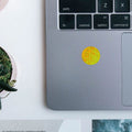 A top-down close-up of a silver laptop keyboard, featuring a circular, yellow AV Edge Protect Filter applied to the palm rest. This non-interference filter uses EF Technology to provide a biological filter for modern technology frequencies, potentially offering mitochondrial support and relief from tech-fatigue for office workers.